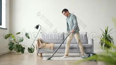 穿休闲服装在家做家务的男人在公寓里吸尘地毯